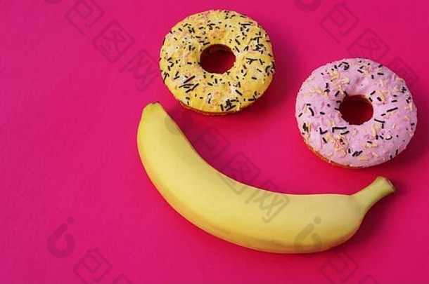 甜甜圈香蕉谎言粉红色的表面形成抽象表情符号微笑前点